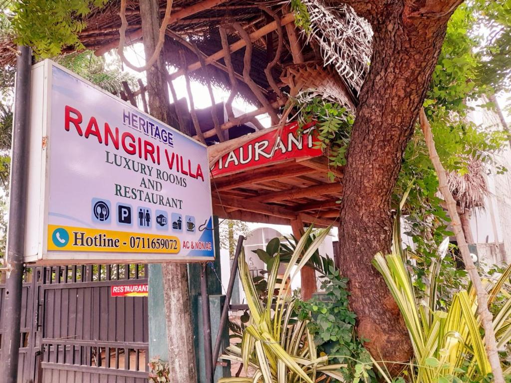 a sign for a restaurant next to a tree at Heritage Rangiri Villa in Dambulla