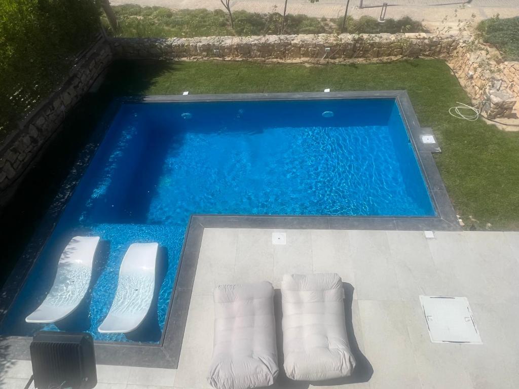 una vista aérea de una piscina con sillas blancas en Seashell villa with private pool en El Alamein