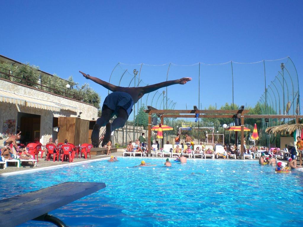 a man is jumping into a swimming pool at Villaggio Turistico Defensola in Vieste