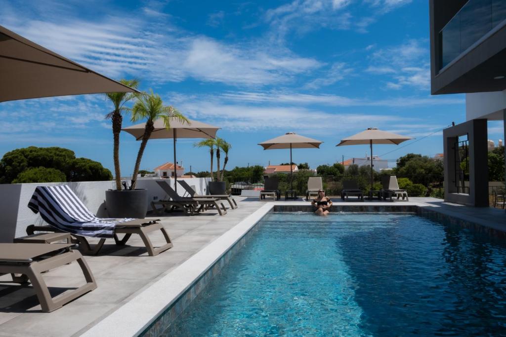 einen Pool mit Stühlen und Sonnenschirmen in einem Resort in der Unterkunft Ria Formosa Guest House in Faro