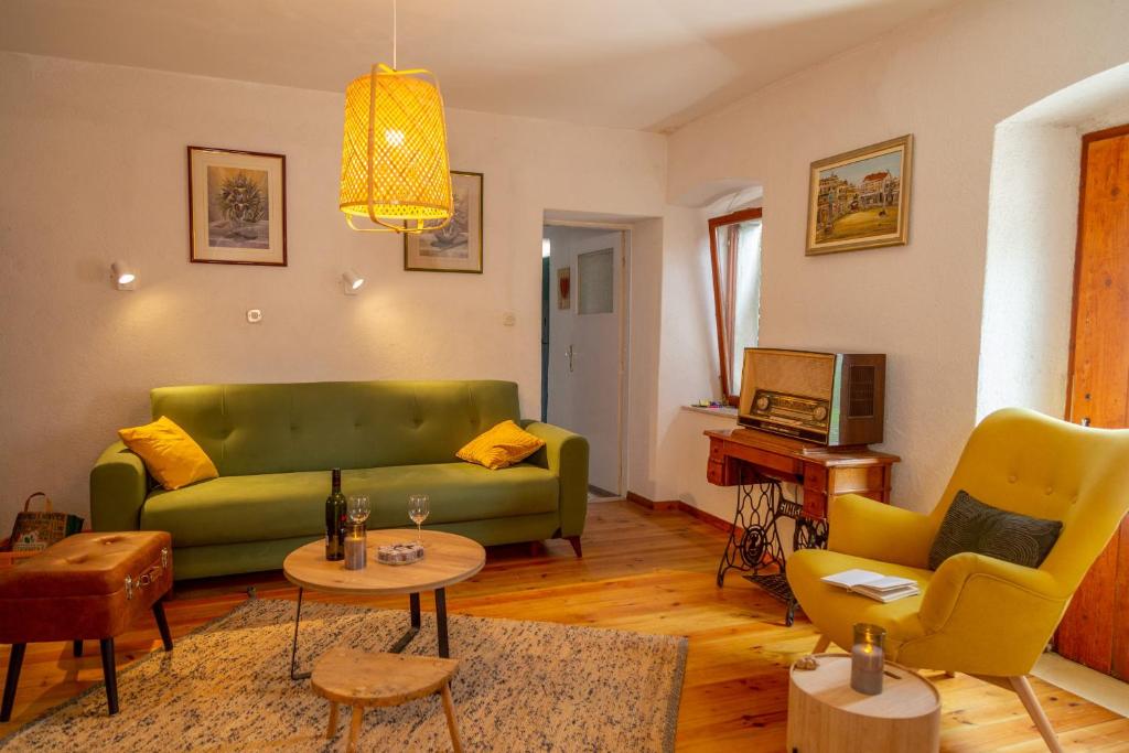 a living room with a green couch and yellow chairs at Authentic stone house Rustica near Makarska Riviera in Lovreć