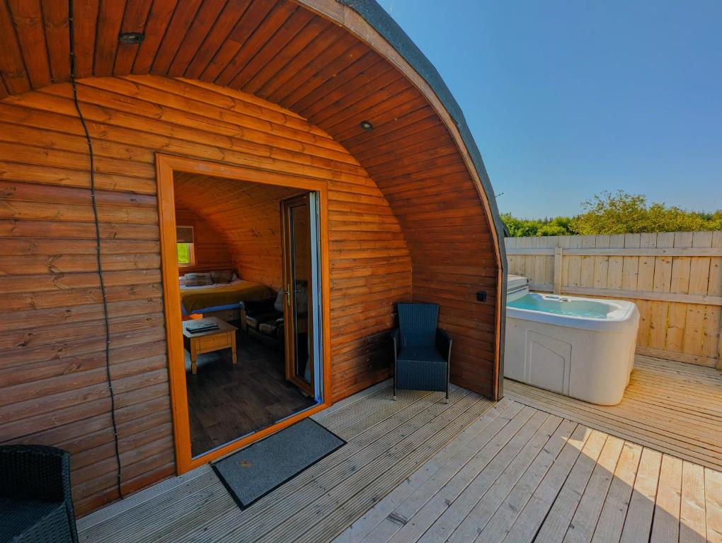 een groot houten huis met een bad en een badkamer bij Pond View Pod 2 with Private Hot Tub -Pet Friendly- Fife - Loch Leven - Lomond Hills in Kelty