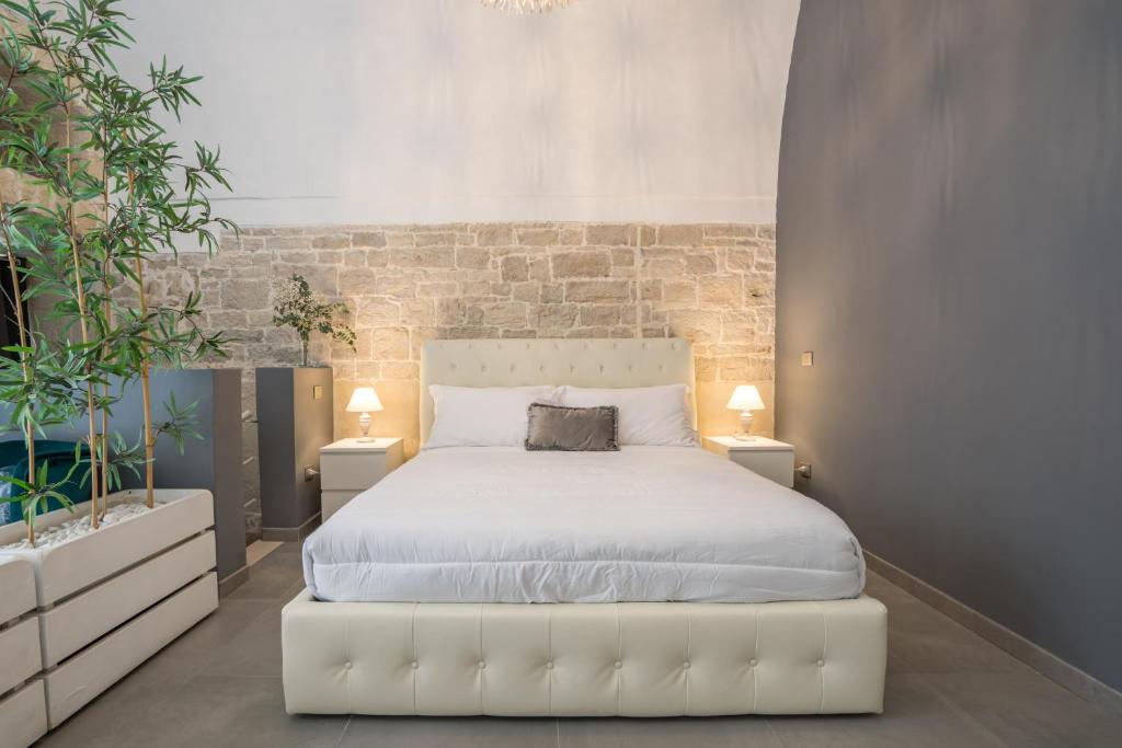 a bedroom with a white bed and a brick wall at 2 Love rooms in Corato