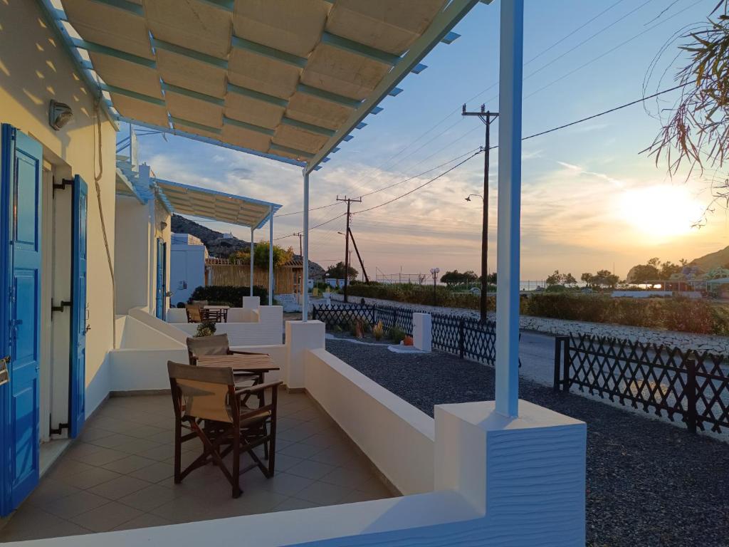 un patio con tavolo, sedie e vista sul tramonto di ΑΥΡΑ Ενοικιαζόμενα Δωμάτια - AVRA Rooms To Let a Galissas