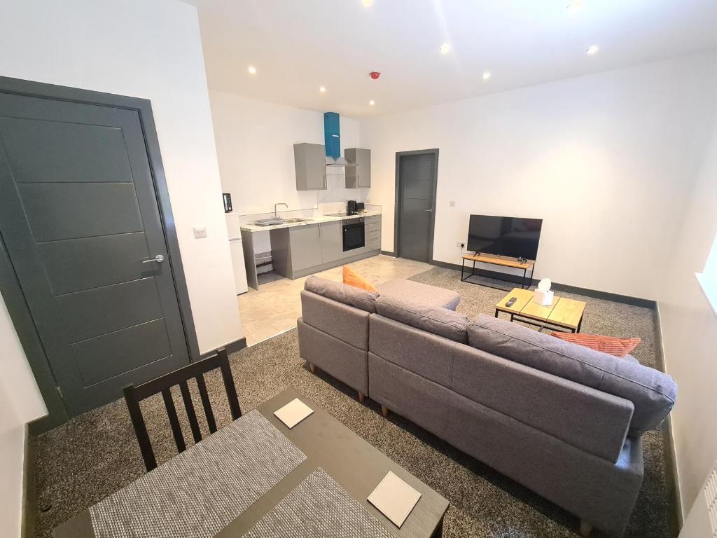 ein Wohnzimmer mit einem Sofa und einer Küche in der Unterkunft Homestay by BIC Oates 4 in Dewsbury