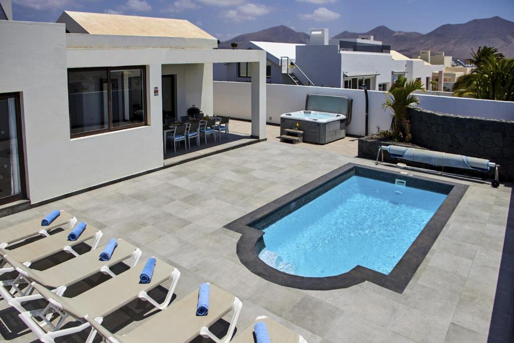 un patio con piscina, sedie e una casa di 205 - Casa Santuario By Villas Now Ltd a Playa Blanca