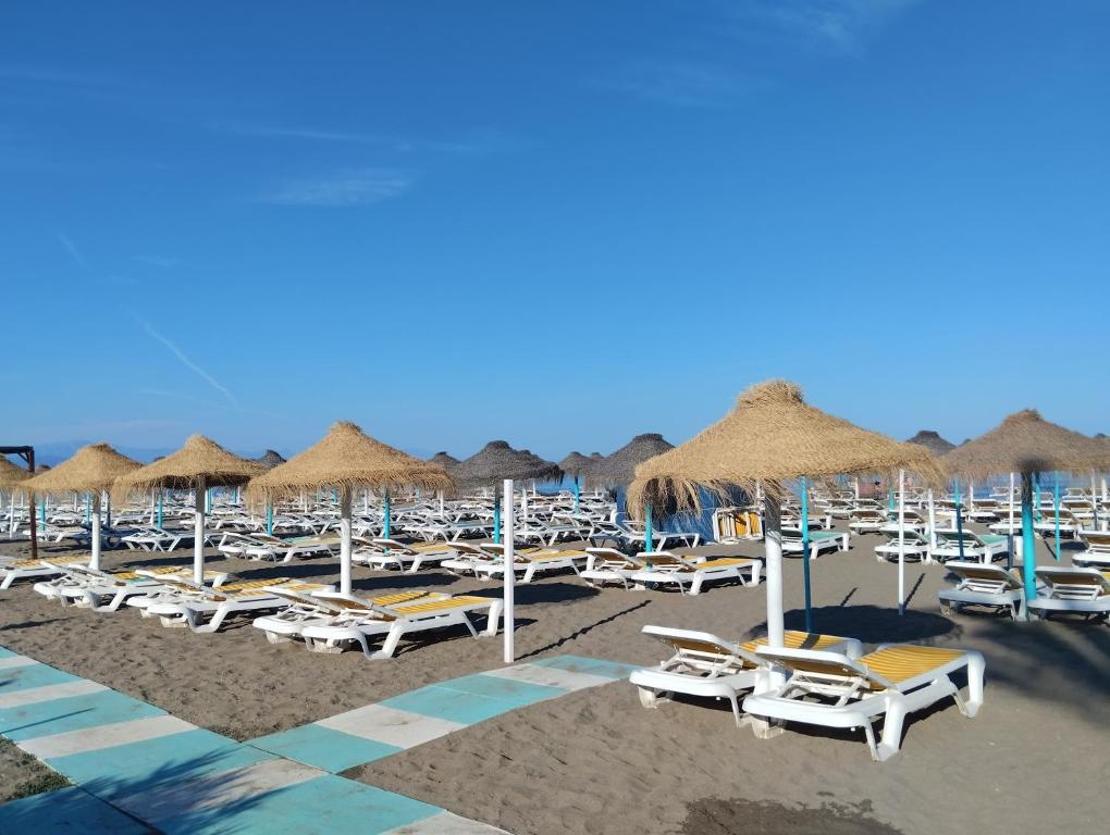 a bunch of chairs and umbrellas on a beach at FUENGIROLA NEW APART. SWEET&BEACH in Fuengirola