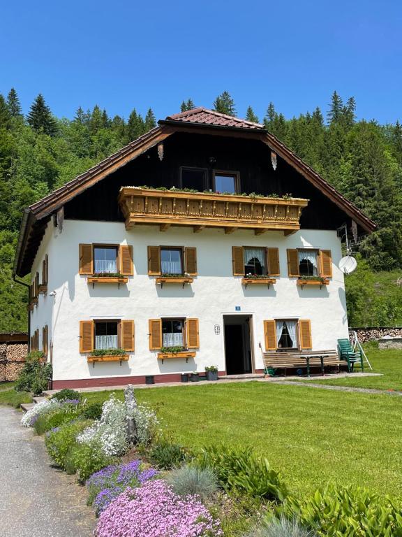 ein großes weißes Gebäude mit Holzfenstern und einem Hof in der Unterkunft Haus Tanne Abtenau in Abtenau