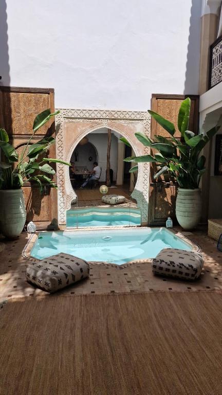 a swimming pool in a house with two potted plants at Riad Des Arts in Marrakesh