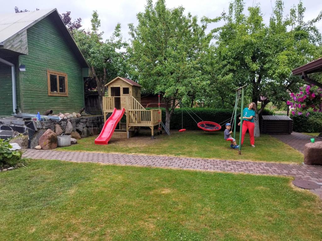 a woman and a child playing in a yard at Spacious & Cozy Apartment with Forest View in Zapyškis