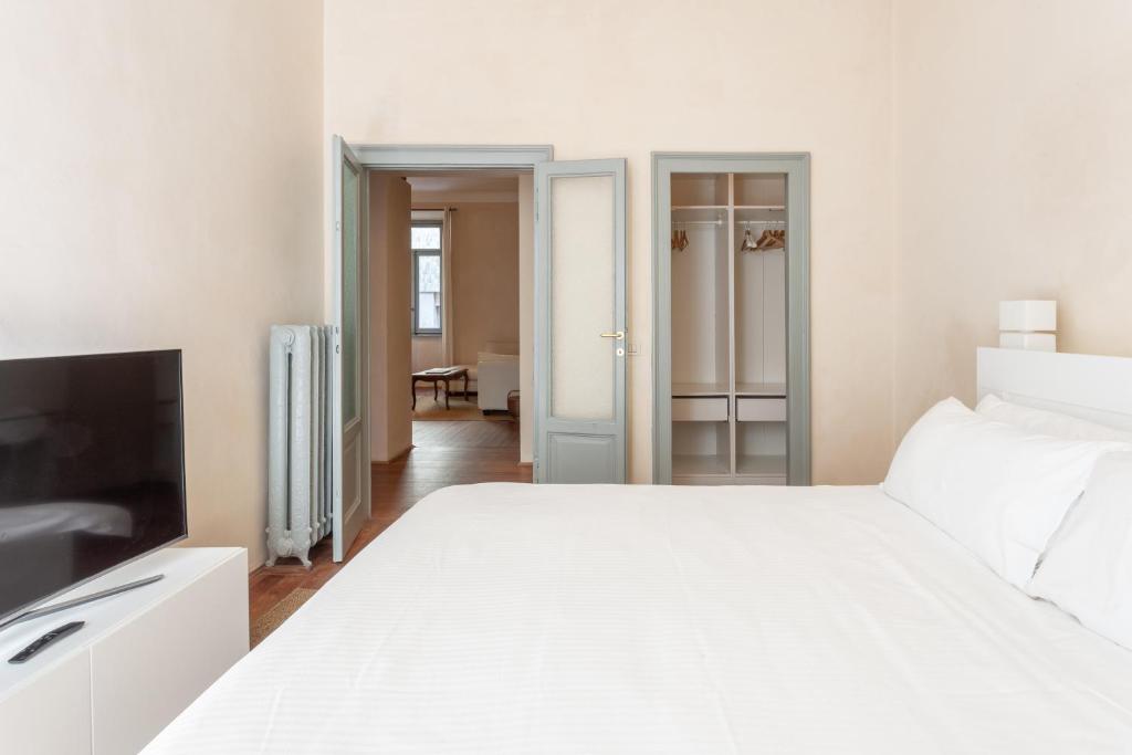 a bedroom with a white bed and a television at Suite Cavour by iCasamia in Varese