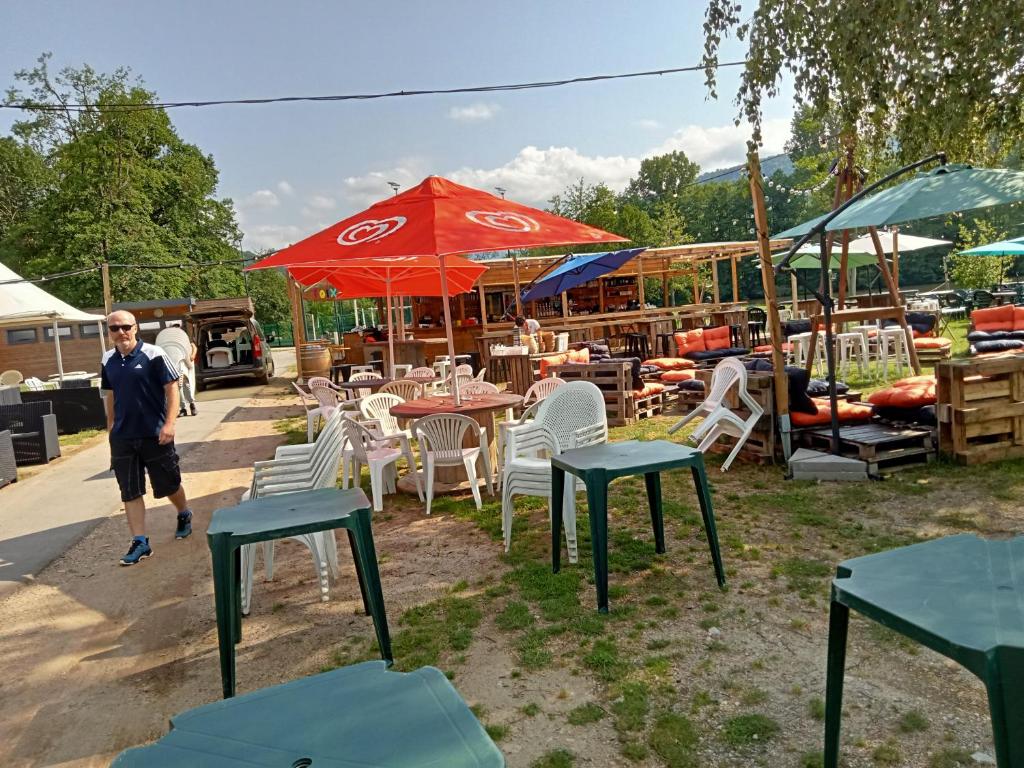 a man standing in front of tables and chairs at mobil-home du lac de Foix in Foix