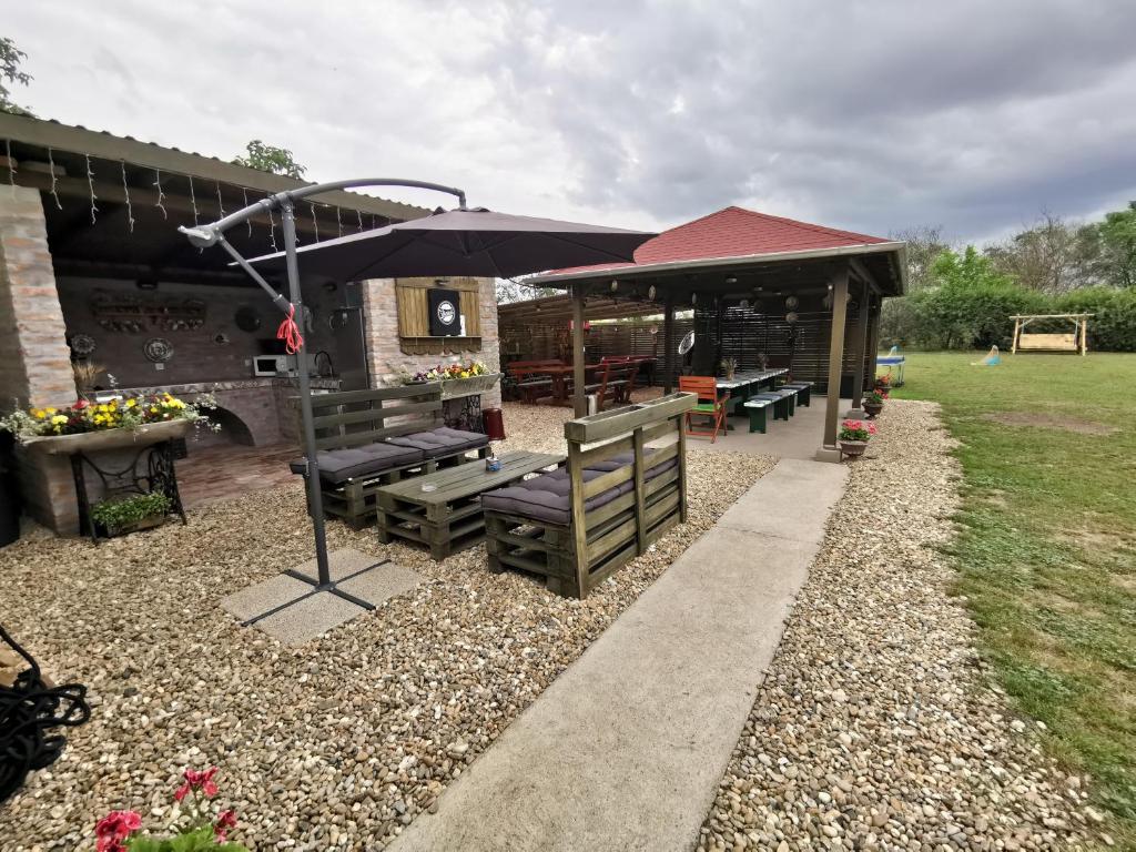 a patio with two benches and an umbrella at Berkó Vendégház in Rákóczifalva