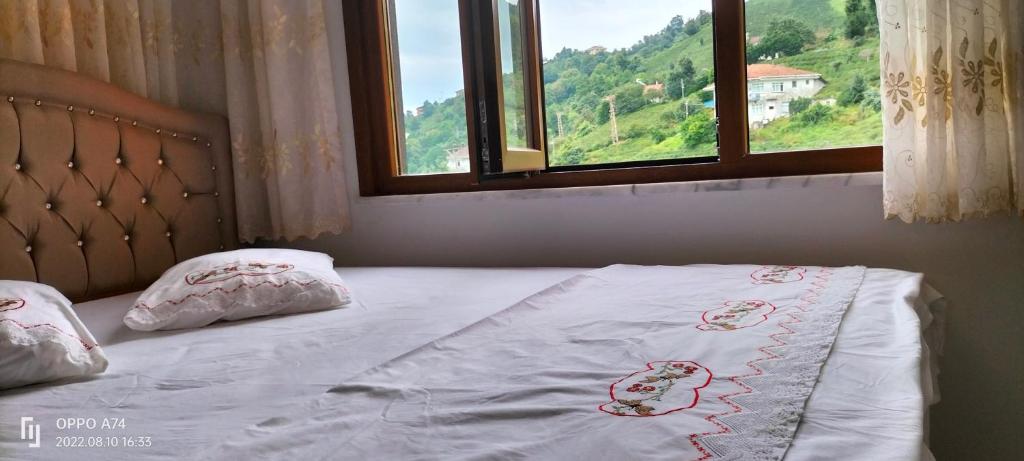 ein Bett mit einer weißen Bettdecke und Kissen mit einem Fenster in der Unterkunft Kemer konak in Cayeli