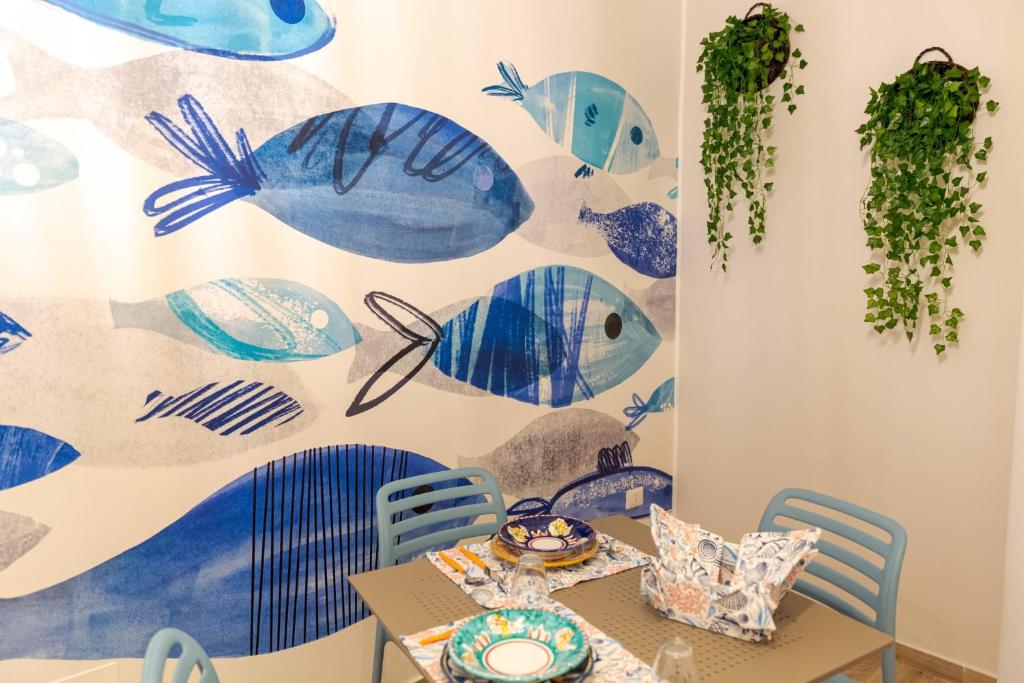uma sala de jantar com uma mesa e peixe azul pintado na parede em Sea Garden Apartments em Ascea