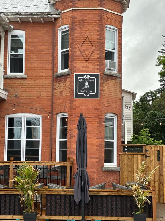 an umbrella in front of a brick building at AUBERGE et BISTRO NAMASTÉ in Lachute