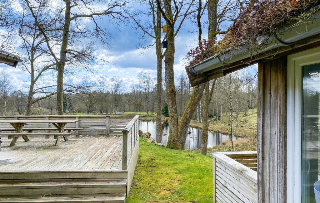 una terraza de madera con mesa de picnic junto a un lago en Awesome Home In tran With Lake View, en Ätran