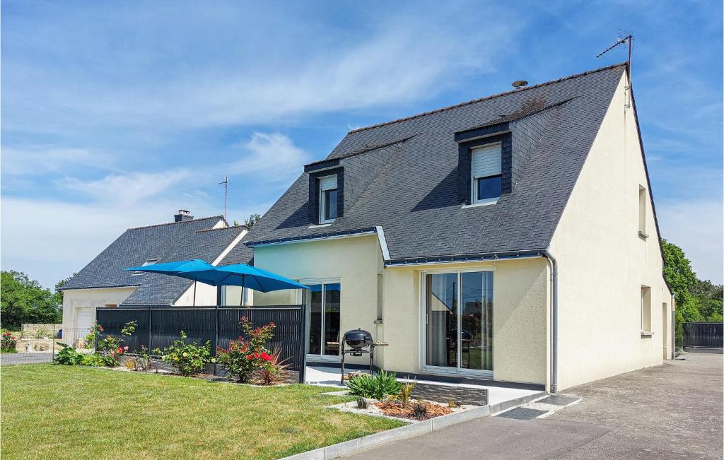 une maison blanche avec un toit noir et un parapluie bleu dans l'établissement 4 Bedroom Amazing Home In Marzan, à Marzan
