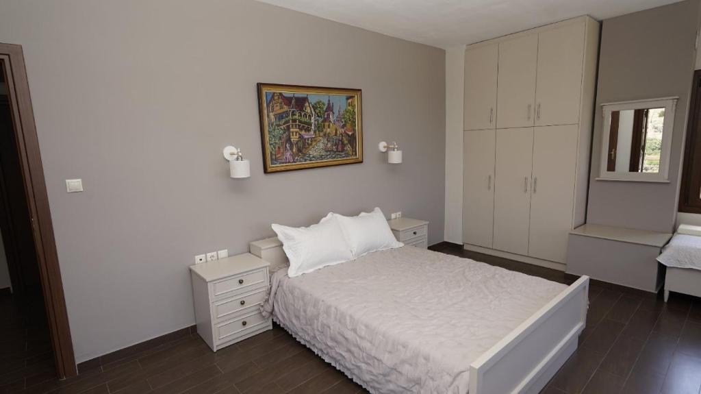 een slaapkamer met een wit bed en een schilderij aan de muur bij Villa Faihs in Afissos
