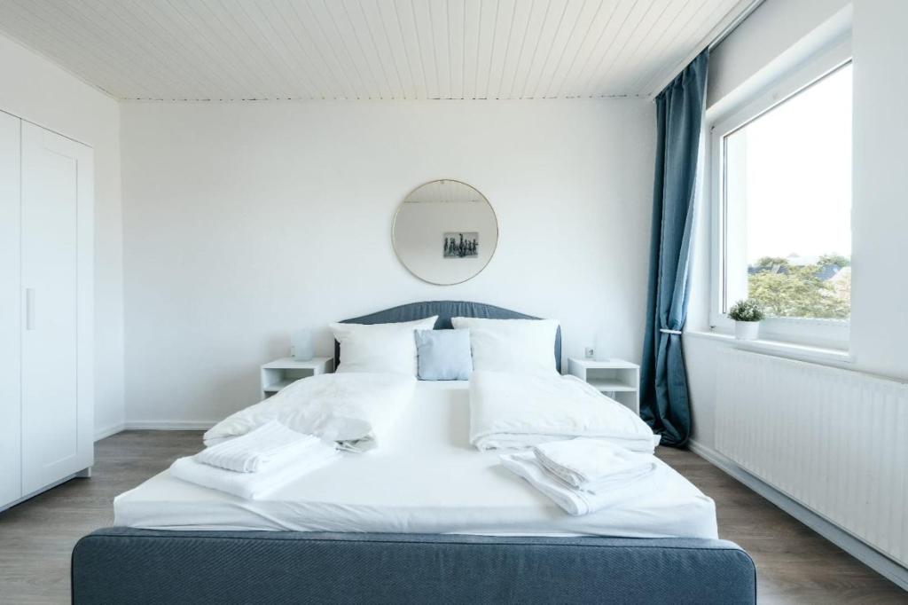 - duże białe łóżko w białym pokoju z oknem w obiekcie Geräumige 2-Zimmer-Wohnung w mieście Neustadt in Holstein