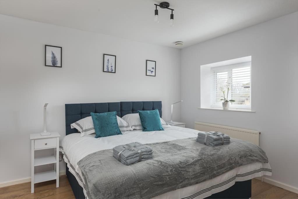 um quarto com uma cama grande e almofadas azuis em Detached House - 5 mins drive to City Centre - Free Parking, Fast Wi-Fi and Smart TV with Sky TV and Netflix by Yoko Property em Milton Keynes