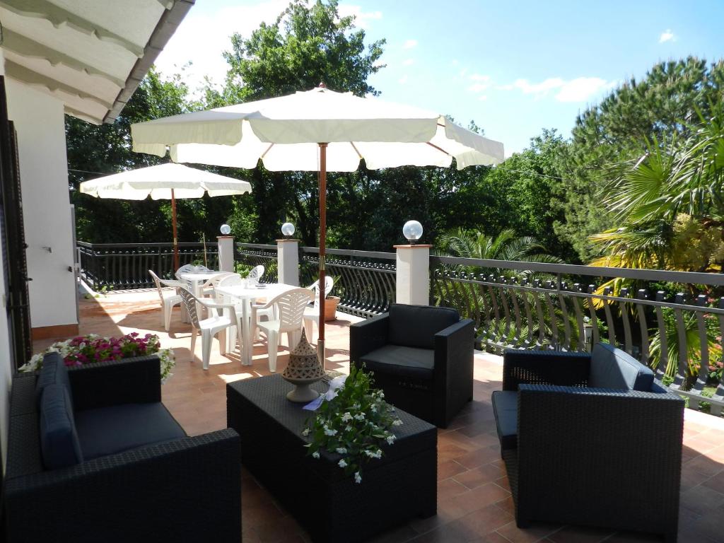un patio con mesa, sillas y sombrilla en B&B Villa Maria, en Terni