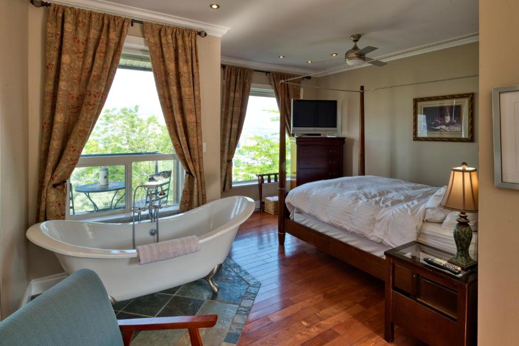 Schlafzimmer mit Badewanne, Bett und TV in der Unterkunft Above the Beach Guest Suites in Penticton