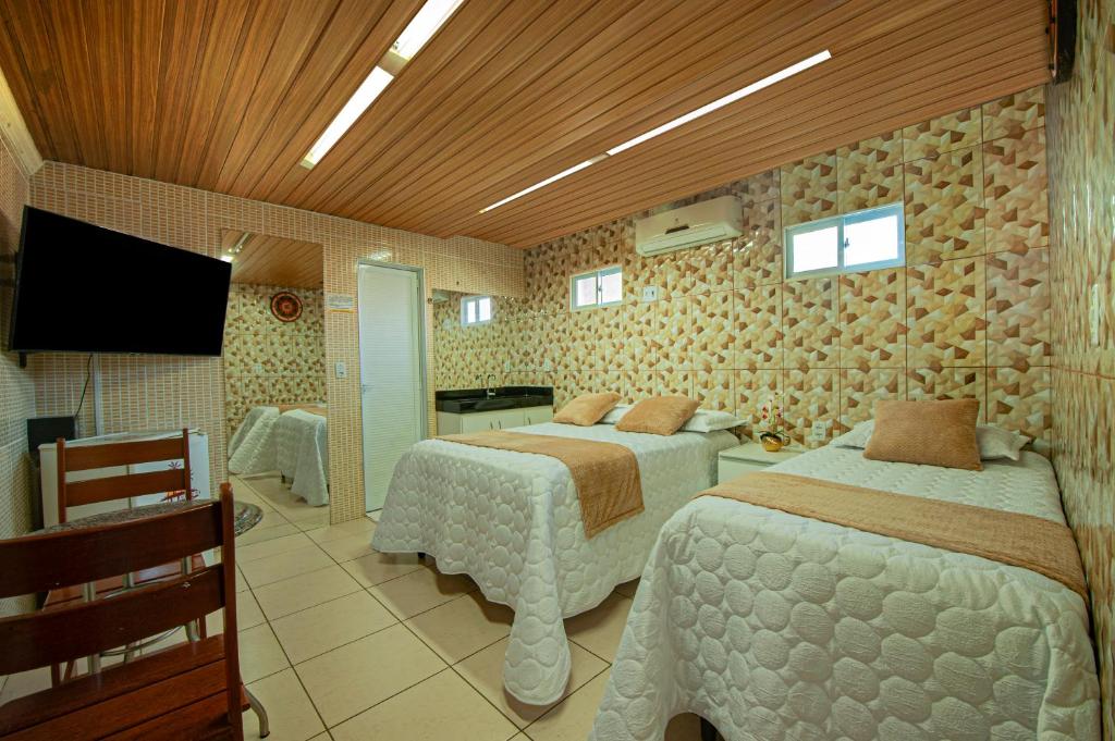 a hotel room with two beds and a television at Pousada Brisa do Atlântico - Praia de Iracema - Próximo a feira da Catedral da sé in Fortaleza