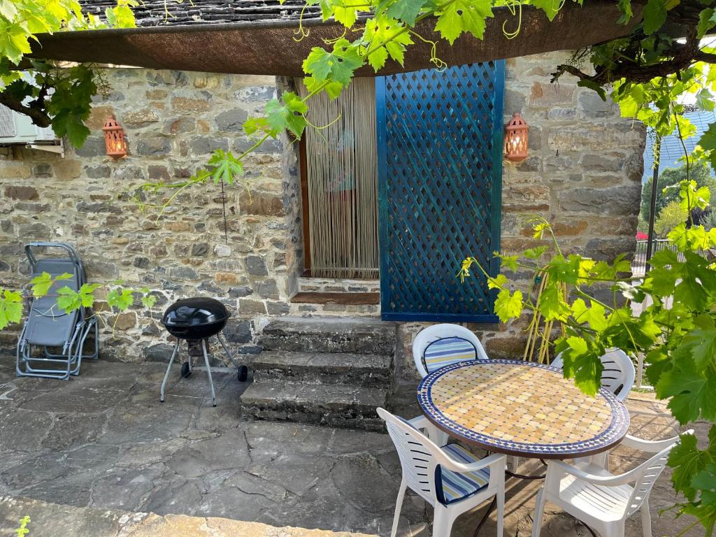 eine Terrasse mit einem Tisch, Stühlen und einem Grill in der Unterkunft La Era in Aínsa