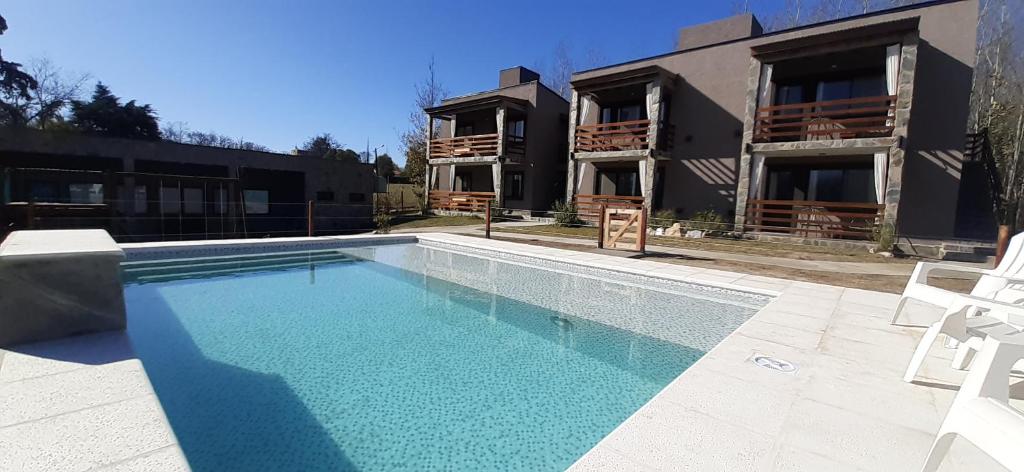 a swimming pool in front of a house at Gemas Apart in Villa Yacanto