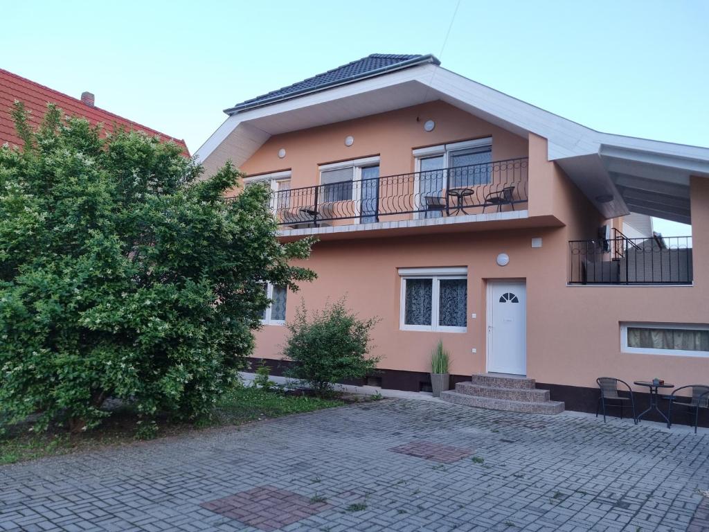 uma casa cor-de-rosa com uma varanda e uma árvore em Lilian apartmanház em Siófok