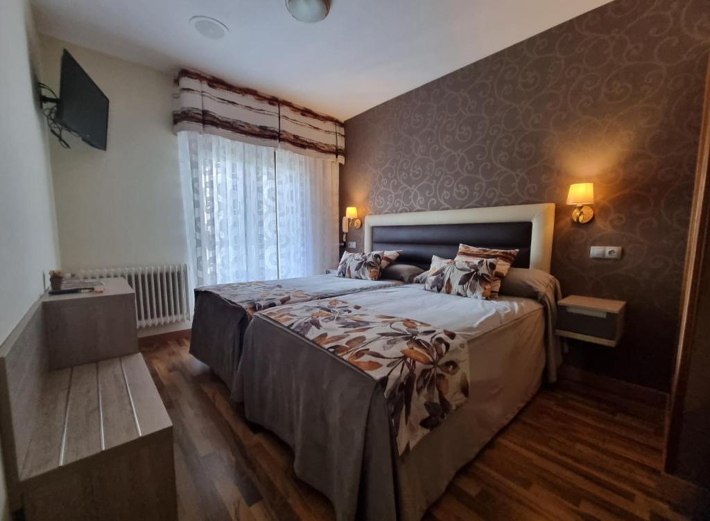 a bedroom with a large bed and a window at Hostal Sainz in Riaño