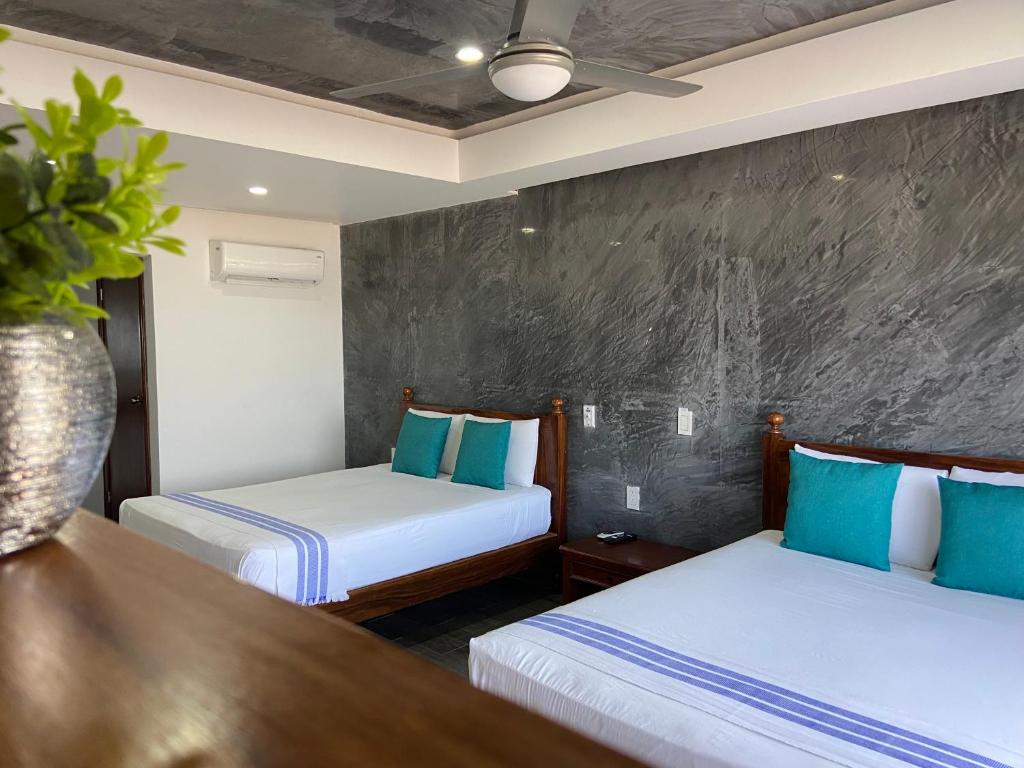 2 Betten in einem Hotelzimmer mit blauen Kissen in der Unterkunft HOTEL EL CORAL in Punta Mita