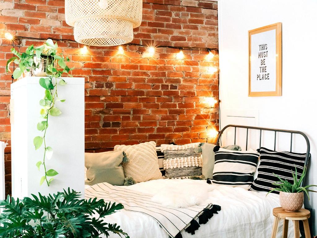 um quarto com uma parede de tijolos e uma cama com almofadas em NurseHaven em Memphis
