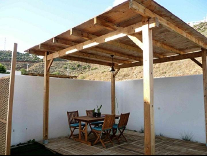 Un pabellón de madera con una mesa y sillas en un patio. en Dúplex casa agua, en San José