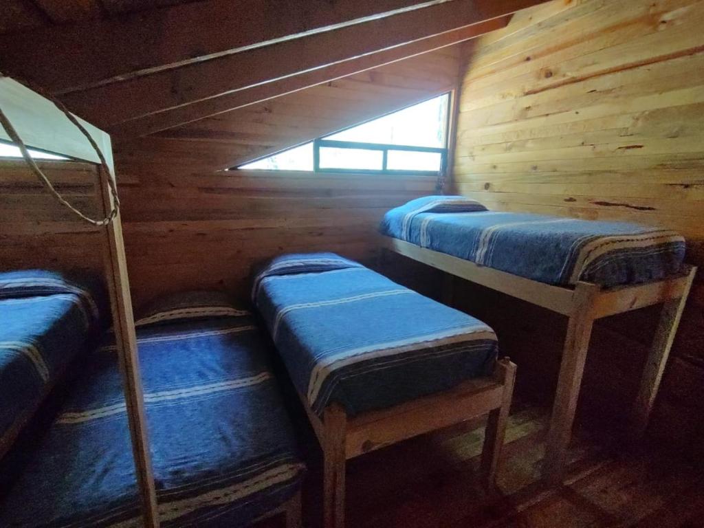 a room with three bunk beds in a cabin at Cabaña Los Nogales in Pátzcuaro