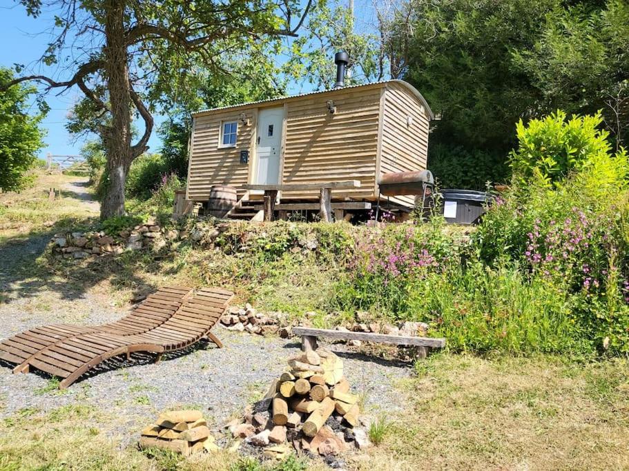 a wooden cabin with a bench and a pile of logs at Plum Hut in Torquay