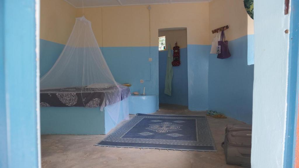 a blue room with a bed with a canopy at Campement & Centre artistique Tilyboo in Kafountine