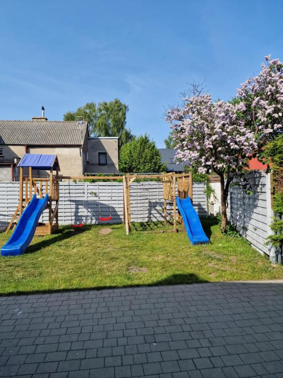un parque infantil con 2 toboganes en un patio en Dom Jastarnia Apartamenty, en Jastarnia