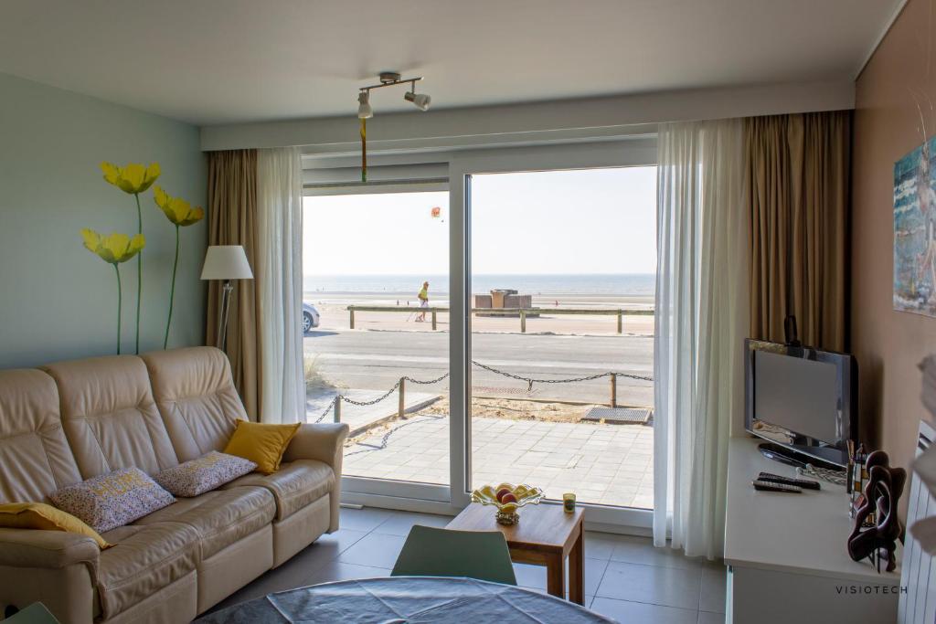 - un salon avec un canapé et une vue sur la plage dans l'établissement L'arc en ciel, à Bray-Dunes
