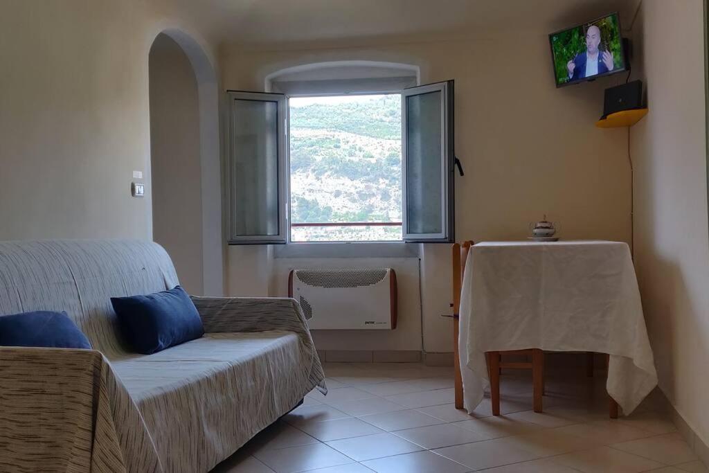 - un salon avec un canapé, une table et une fenêtre dans l'établissement Dolce Vita Alta Ventimiglia, à Vintimille