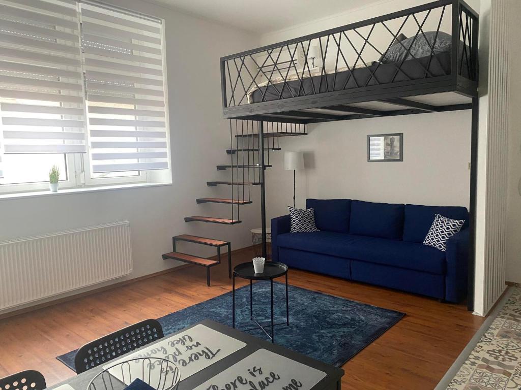 a living room with a blue couch and a loft bed at Víztorony Apartmanok Siófok in Siófok