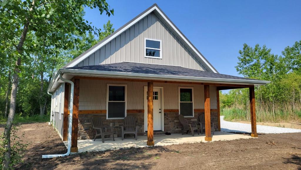 een klein huis met een veranda en stoelen aan de voorkant bij Brightstone Lake Cabin 1 in Fair Oaks