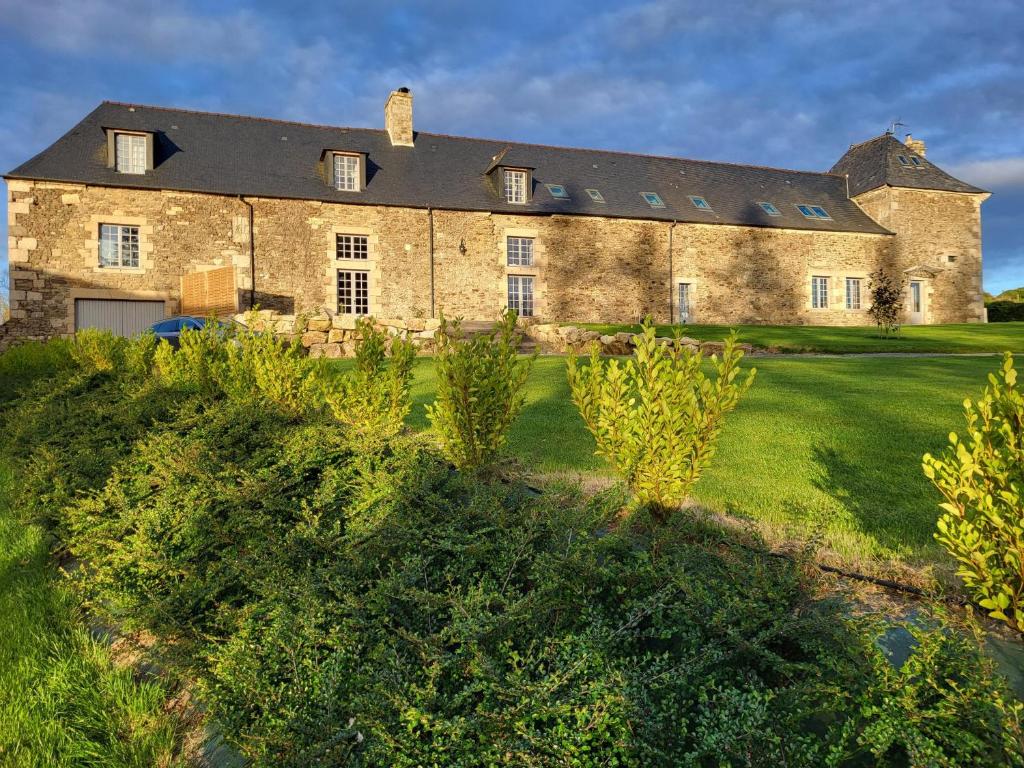 uma grande casa de pedra com um quintal verde em Manoir de La Garaye - Suite Parentale em Taden