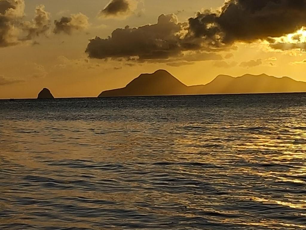 een zonsondergang over de oceaan met bergen op de achtergrond bij West Indies in Caritan