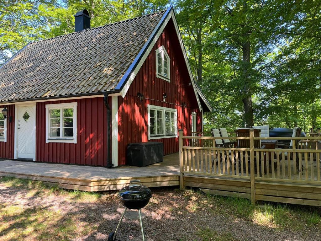 a red house with a deck and a grill at Blueberry Hill in Skånes Fagerhult