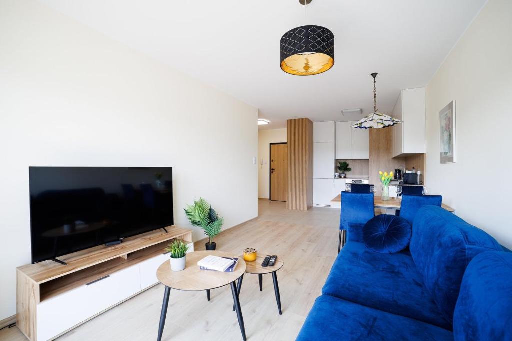 a living room with a blue couch and a large tv at Apartament Marinus ProstyWynajem Gdańsk Brzeźno in Gdańsk