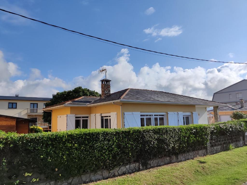 a yellow house with a hedge in front of it at Casa A Mariña in Barreiros