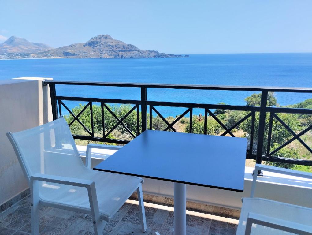 einen Tisch und Stühle auf einem Balkon mit Meerblick in der Unterkunft Fotmar in Plakias