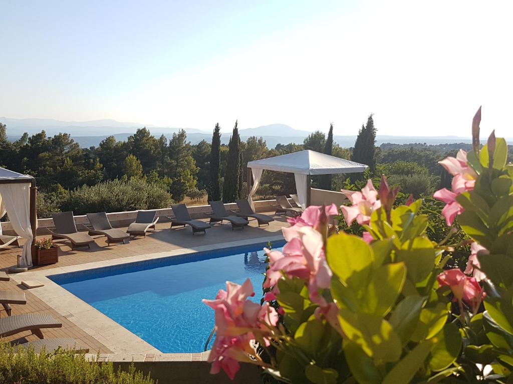 uma villa com piscina, cadeiras e flores em La Petite Auberge em Tourtour